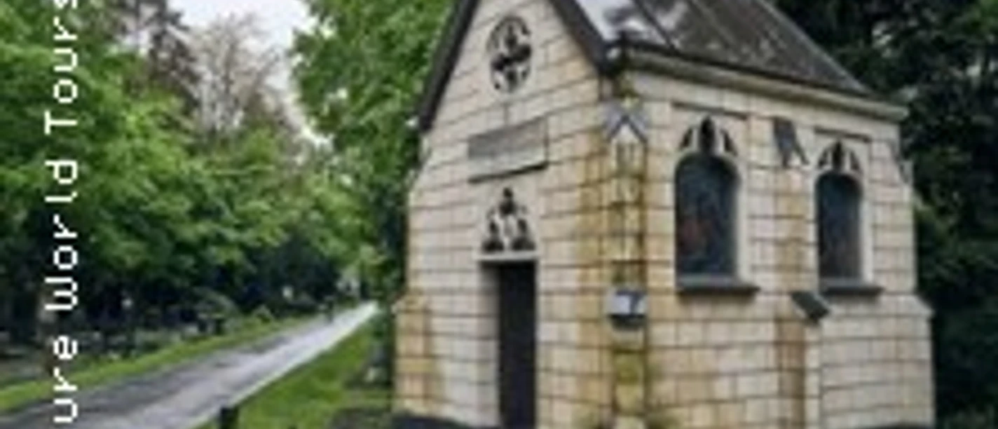 Kleines steinernes Mausoleum steht an einem kurvigen Weg zwischen hohen Bäumen.