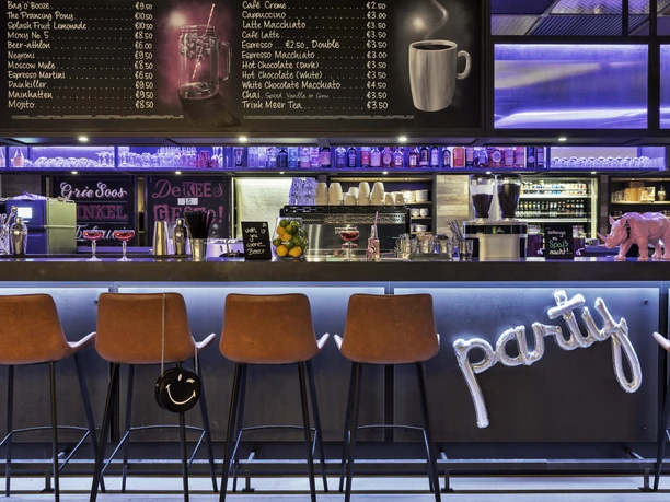Moxy Frankfurt East - Bar Moderne Bar mit Theke und Party-Schriftzug.