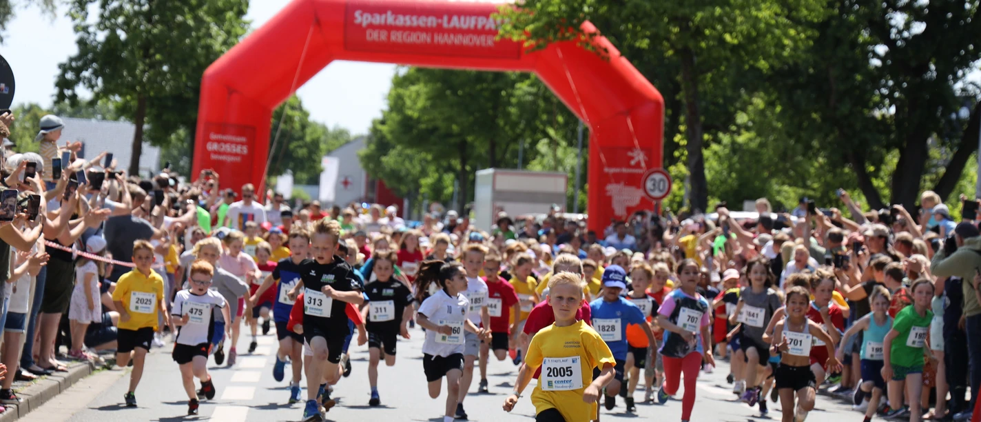 Stadtlauf_3626-os A 1366.jpg Children start the city run under a red archway, surrounded by rows of cheering spectators.