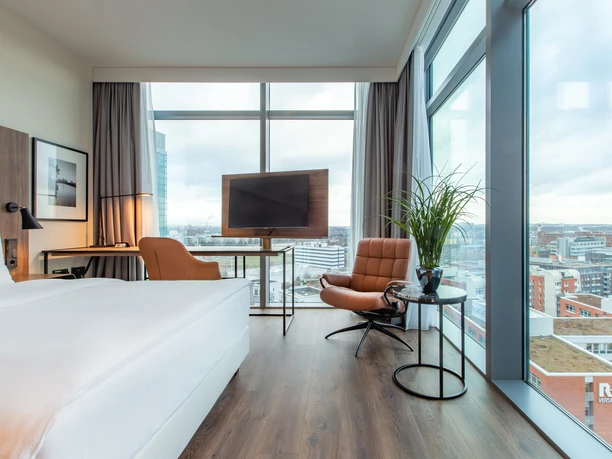 Radisson Blu Hotel, Frankfurt - Hotel rooms Bright hotel room with panoramic windows and city view.