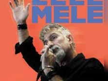 Ein Sänger performt mit leidenschaftlicher Gestik vor einem orangefarbenen Hintergrund.