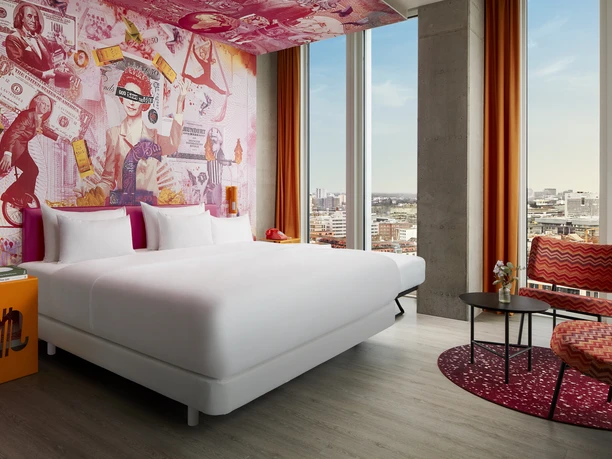 nhow Frankfurt - Hotelzimmer Bunt gestaltetes, stylisches Hotelzimmer mit Blick auf die Frankfurter Skyline.