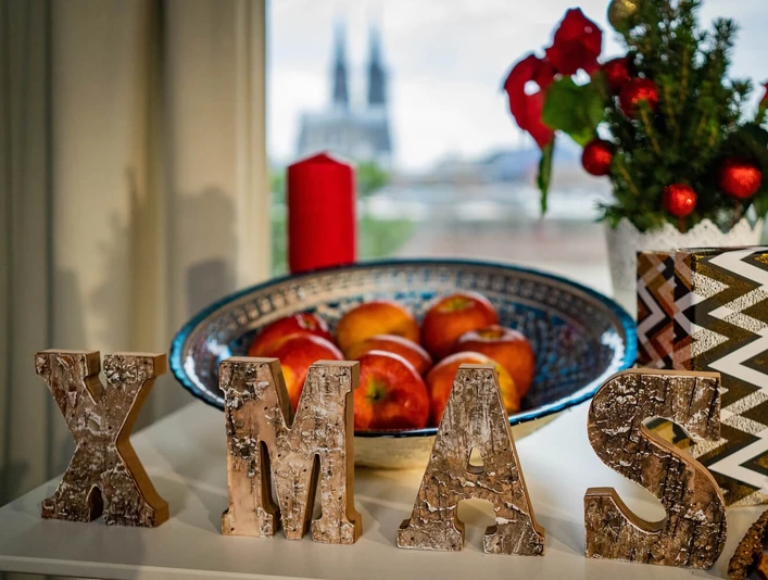 X-mas at the view Cologne Weihnachtliche Dekoration mit XMAS-Schriftzug, Äpfeln, Kerzen und Dom in KölnChristmas decorations with XMAS lettering, apples, candles and Cologne Cathedral