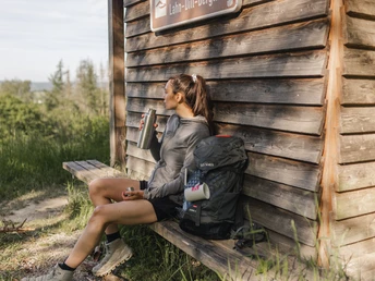 Wanderin macht Pause an der Schutzhütte am Aussichtspunkt "Westerwaldblick"