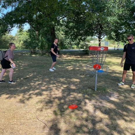RS31748_Sportliches Wolfsburg_29.08._3-scr.jpg Drei Personen spielen im Park Discgolf