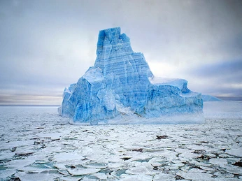 Ein imposanter blauer Eisberg schwimmt majestätisch im eisbedeckten Meer.An imposing blue iceberg floats majestically in the ice-covered sea.