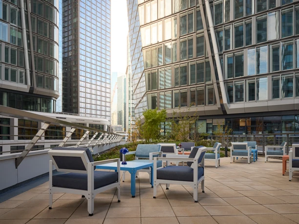 Kimpton Main Frankfurt - Terrasse Terrasse mit blauen Sesseln inmitten von Hochhäusern.