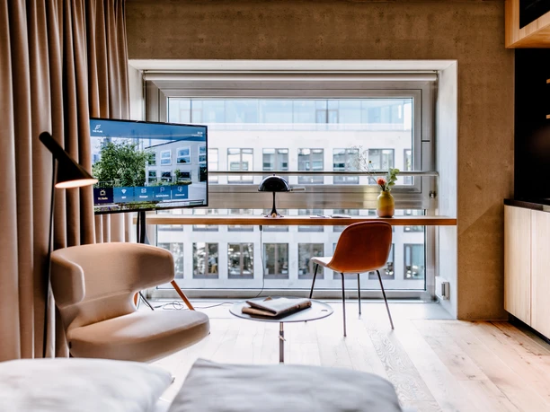 THE FLAG West M - Hotelzimmer Modernes Hotelzimmer mit Schreibtisch am Fenster und TV.