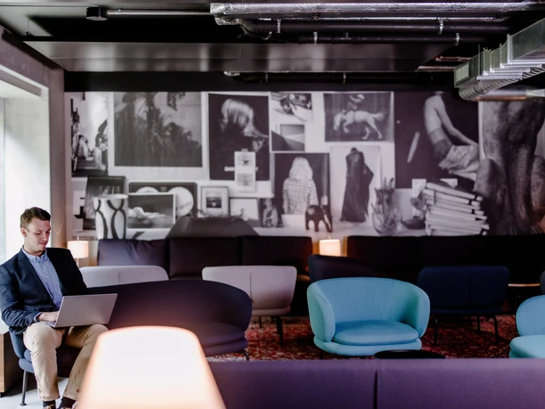 THE FLAG West M - Lounge Stylische Lounge mit Fotowand und bunten Sesseln.