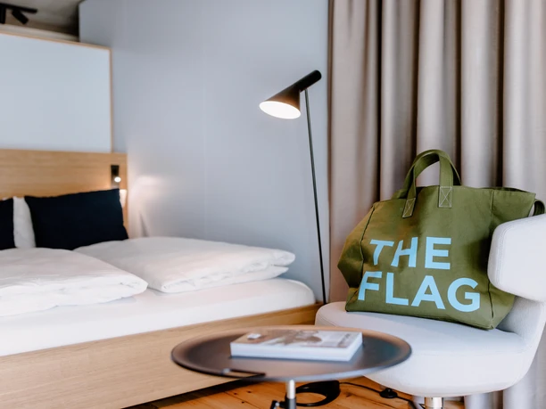 THE FLAG West M - Hotel room Modern hotel room with bed, armchair and bag.
