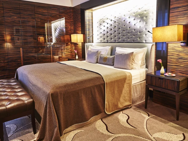 Steigenberger Icon Frankfurter Hof - Hotelzimmer Hotelzimmer in warmen Erdtönen mit Ambientebeleuchtung und Boxspringbett.