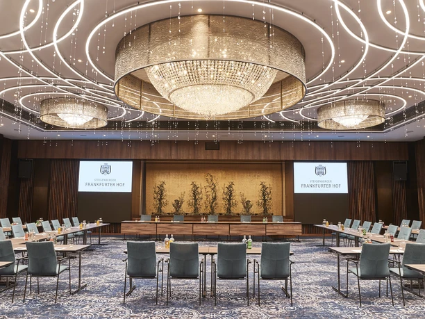 Steigenberger Icon Frankfurter Hof - Festsaal Tagungsraum mit aufwendiger Deckenbeleuchtung, bestuhlt und ausgerichtet auf das Podium.