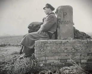 01 Heinrich Jansen....jpg Schwarzweißfoto eines Soldaten in Uniform, der an einem Grenzstein sitzt.