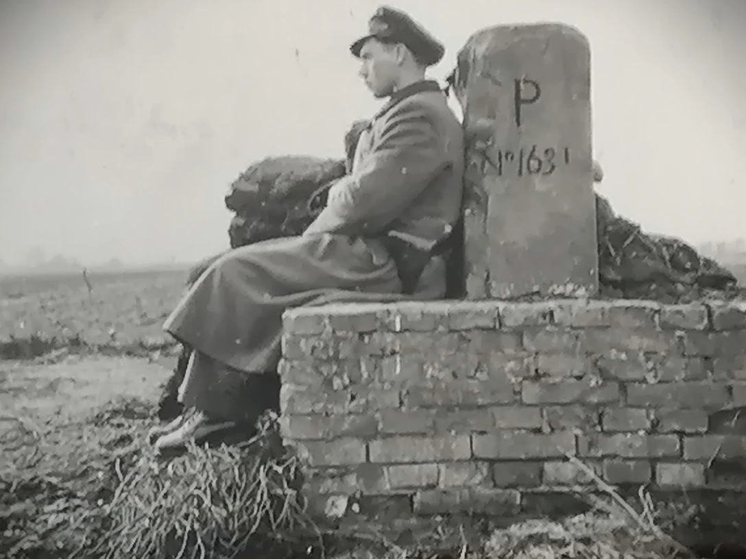 01 Heinrich Jansen....jpg Schwarzweißfoto eines Soldaten in Uniform, der an einem Grenzstein sitzt.