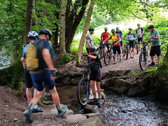 Gruppe Mountainbiker bei Bachüberquerung