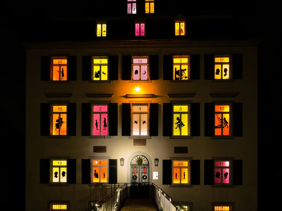 Advent calendar at the Holzhausenschlösschen Beleuchtetes Haus mit farbigen Adventsfenstern und Schattenfiguren.Illuminated house with colorful Advent windows and shadow figures.