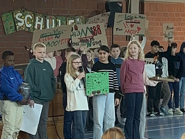 Der vierte Jahrgang hatte sich intensiv mit den Mooren beschäftigt..JPEG Kinder präsentieren in einer Turnhalle selbstgestaltete Plakate zum Thema Schutz der Moore.