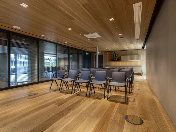 b'mine Frankfurt Airport - Gallery Meetingraum mit Holzboden, Holzdecke und Stuhlreihen.