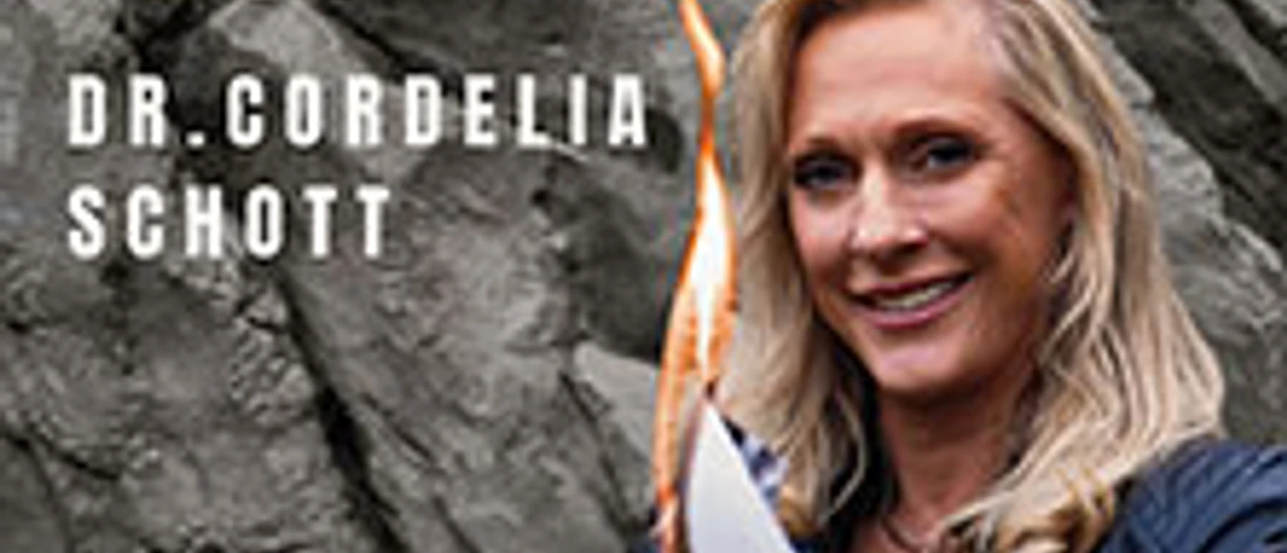 Dr. Cordelia Schott hält ein brennendes Blatt vor einer dunklen Felswand in der Hand.