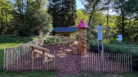 Murmelbahn Neustadt Holzspielplatz mit Murmelbahn und Pilzturm im Grünen Neustadt, umgeben von Bäumen und Holzzaun.