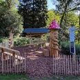 Murmelbahn Neustadt Holzspielplatz mit Murmelbahn und Pilzturm im Grünen Neustadt, umgeben von Bäumen und Holzzaun.