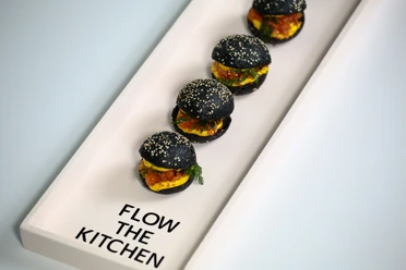 FLOW THE KITCHEN - Burger Eine weiße, moderne Vorlegeplatte mit Mini-Burgern.
