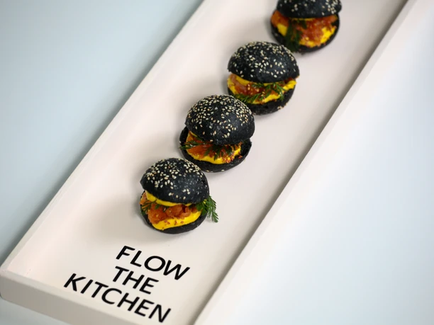 FLOW THE KITCHEN - Burger Eine weiße, moderne Vorlegeplatte mit Mini-Burgern.