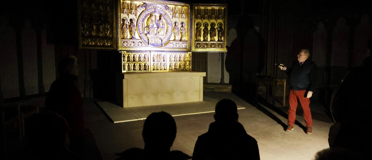 Auf dem Bild sieht man eine Gruppe von Menschen die mit Taschenlampen im Dom stehen.