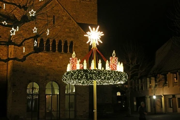 Auf dem Bild sieht man einen leuchtenden Adventskranz, direkt vor dem Mindener Dom.