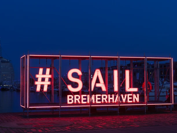 MII_2972 (c) Helmut Gross_Erlebnis Bremerhaven.jpg Leuchtinstallation mit rotem Schriftzug #SAIL Bremerhaven am Hafen vor nächtlicher Kulisse