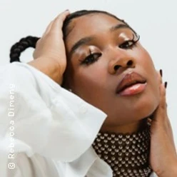 Rose May Alaba im Porträt mit weißem Oberteil und modischem Perlenkragen.