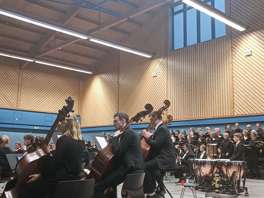 Landesjugendorchester Bremen in Hambergen Orchester und großer Chor treten in einer holzverkleideten Sporthalle auf.