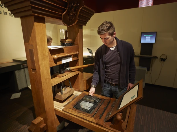 Discover the Book of Books - Printing Press Person working on an old printing press.