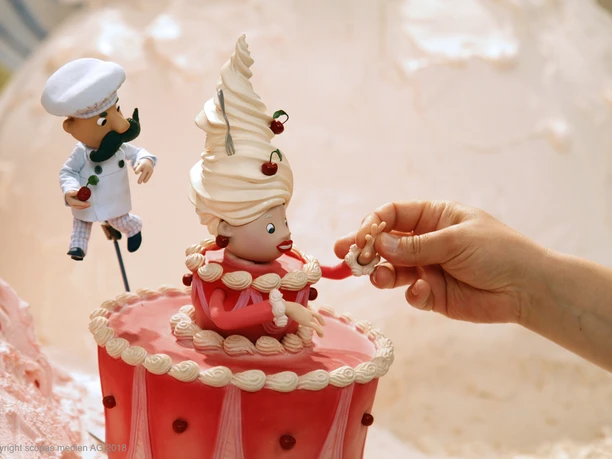 Trickfilmland - Animation Tortenfrau Animationsfigur in Frauenform steht als Dekofigur auf einer Torte.