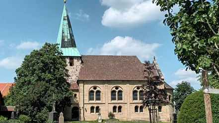 Evangelische Kirche in Groß Mahner mit grünem Turmhelm, Sandsteinmauern und gepflegtem Kirchhof.