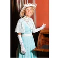 Gräfin Julia NEU Zeitreiseführung Schloss Evenburg The countess in period dress with a light blue dress and hat stands smiling next to an old writing desk