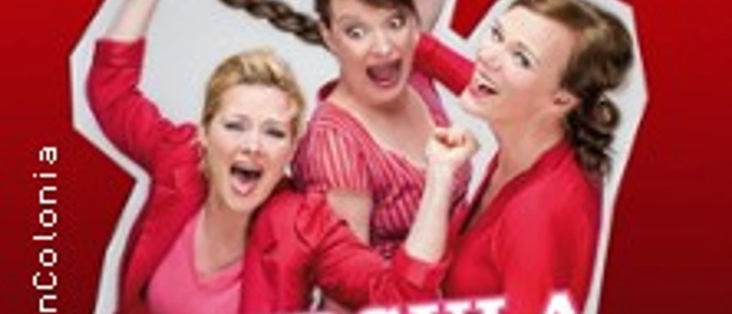 Drei Frauen in roten Outfits lachen fröhlich vor einem roten Hintergrund.