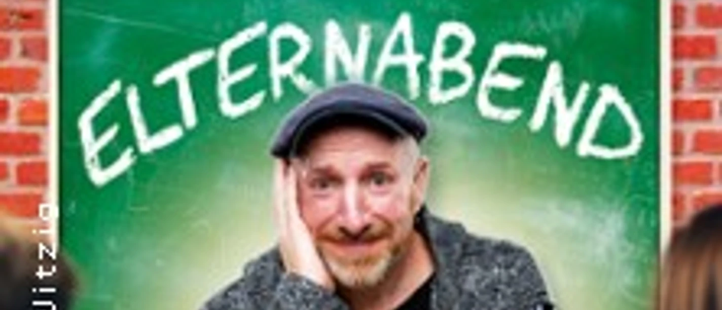 Martin Schopps sitzt vor einer Tafel mit dem Schriftzug "Elternabend", umringt von Wein.