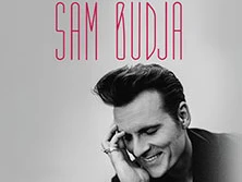 Porträt eines lächelnden Mannes, der auf einem monochromen Hintergrund posiert, begleitet von Text "One Night With Sam Budja".