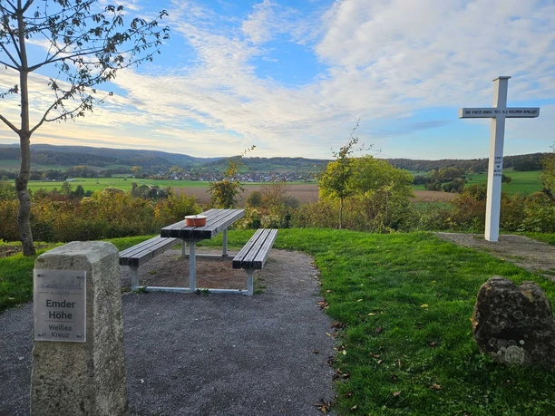 Aussichtspunkt mit Sitzbank, Weißem Kreuz und Blick über Felder und Hügel bei Bad Driburg-Alhausen.
