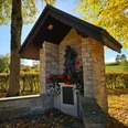 Erpentrup Bildstock Steinerner Bildstock mit Marienfigur und Blumen, umgeben von herbstlichen Bäumen in Bad Driburg-Erpentrup.