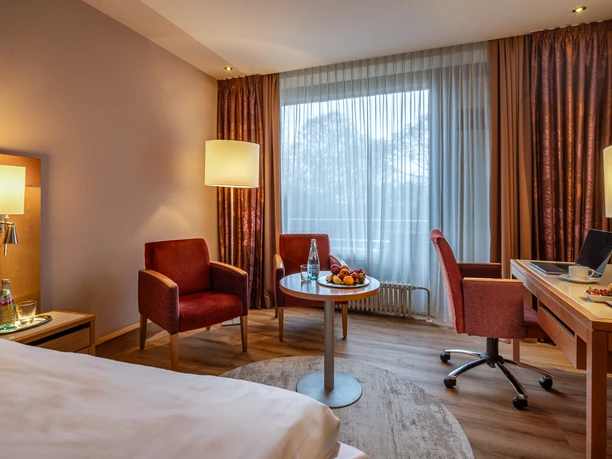 Dolce by Wyndham Bad Nauheim - Hotelzimmer Hotelzimmer mit roten Sesseln und Schreibtisch.