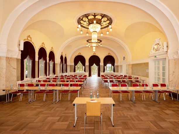 Dolce by Wyndham Bad Nauheim - Saal Prunkvoller Saal mit Gewölbe, Kronleuchtern und roten Stühlen.