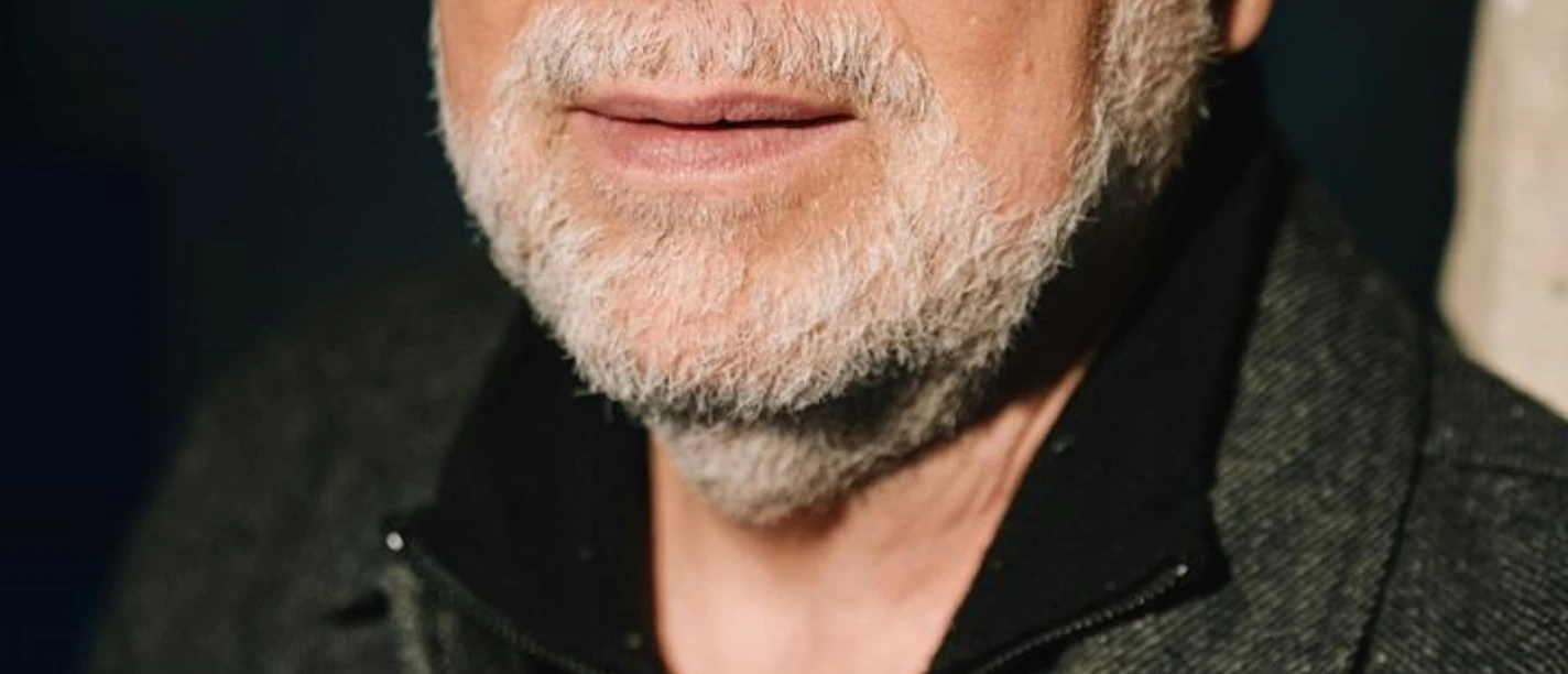 Jürgen Kehrer Webversion.jpg Man with gray beard wears gray wool cap, black glasses, black zippered sweater and gray coat.