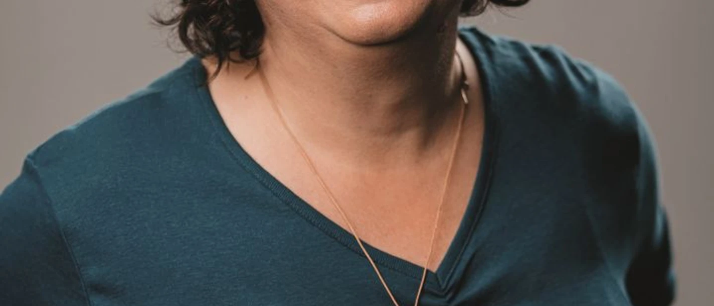 Oswald Susanne Webversion.jpg Persoon met schouderlang krullend haar draagt een donkergroen topje en een ronde houten ketting.