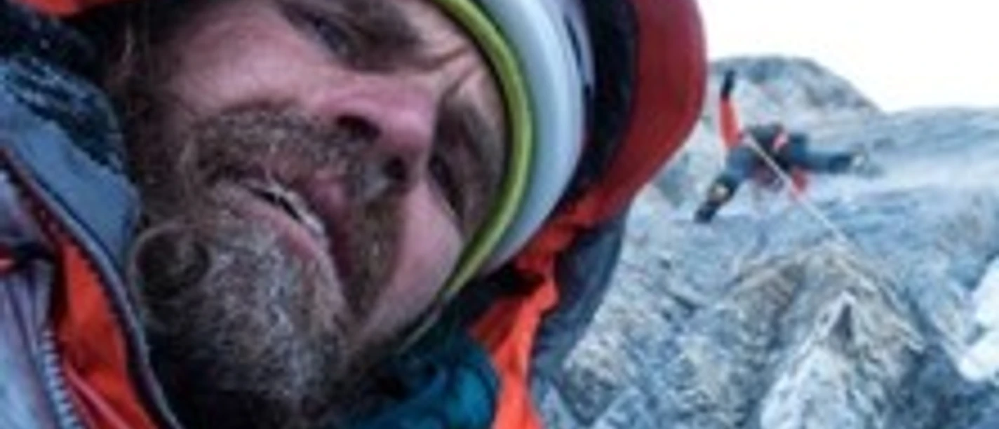 Thomas Huber klettert konzentriert an einer felsigen Bergwand, im Hintergrund ein weiterer Kletterer.