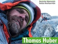 Thomas Huber klettert konzentriert an einer felsigen Bergwand, im Hintergrund ein weiterer Kletterer.