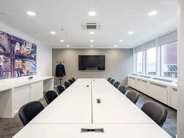 Fraport Conference Center - Konferenzraum Konferenzraum mit langem Tisch, Screen und Wandbild.