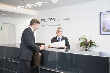 Fraport Conference Center - Empfangssituation Empfangssituation am Counter mit Gast und Mitarbeiter.