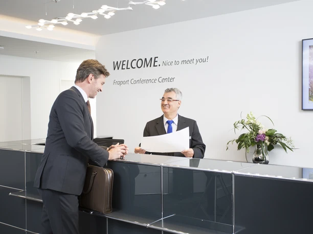 Fraport Conference Center - Empfangssituation Empfangssituation am Counter mit Gast und Mitarbeiter.